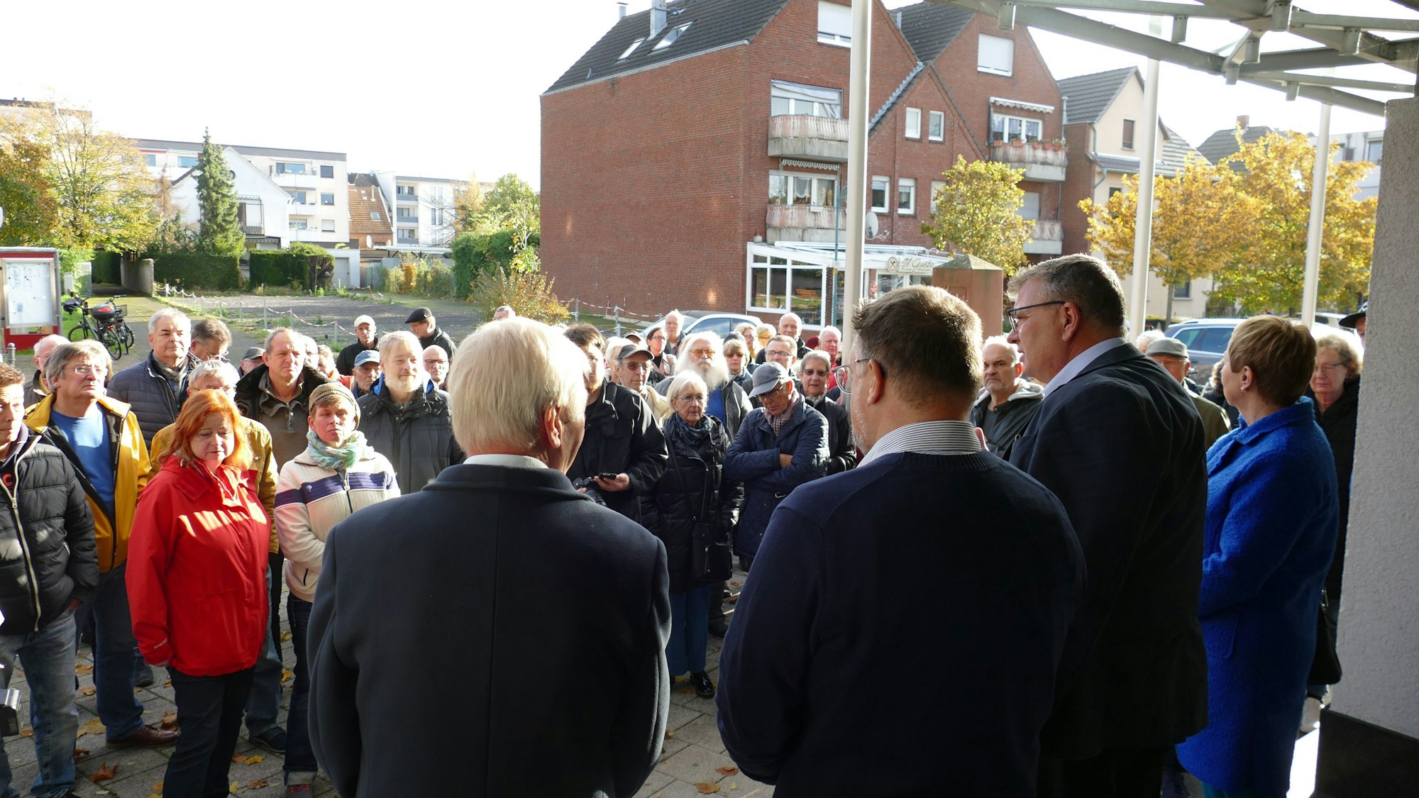 Männer und Frauen stehen vor einem Verwaltungsgebäude.