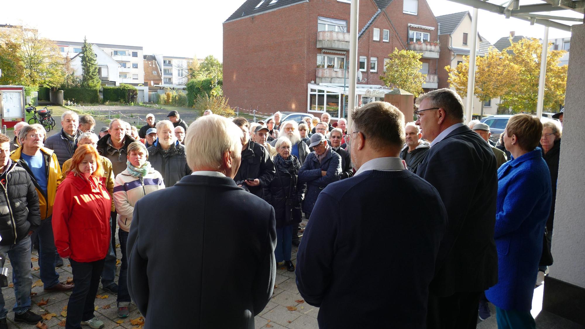 Der ehemalige Niederkasseler Bürgermeister Stephan Vehreschild diskutiert vor dem Rathaus mit Bürgerinnen und Bürgern, die gegen die Erhöhung der Grundsteuer B protestieren.