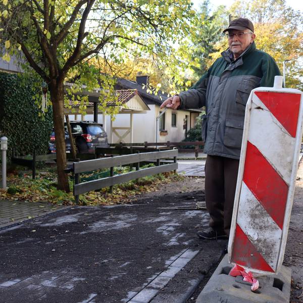 Michael Bolten zeigt auf die abschüssige Zuwegung zwischen Straße und seinem Grundstück.