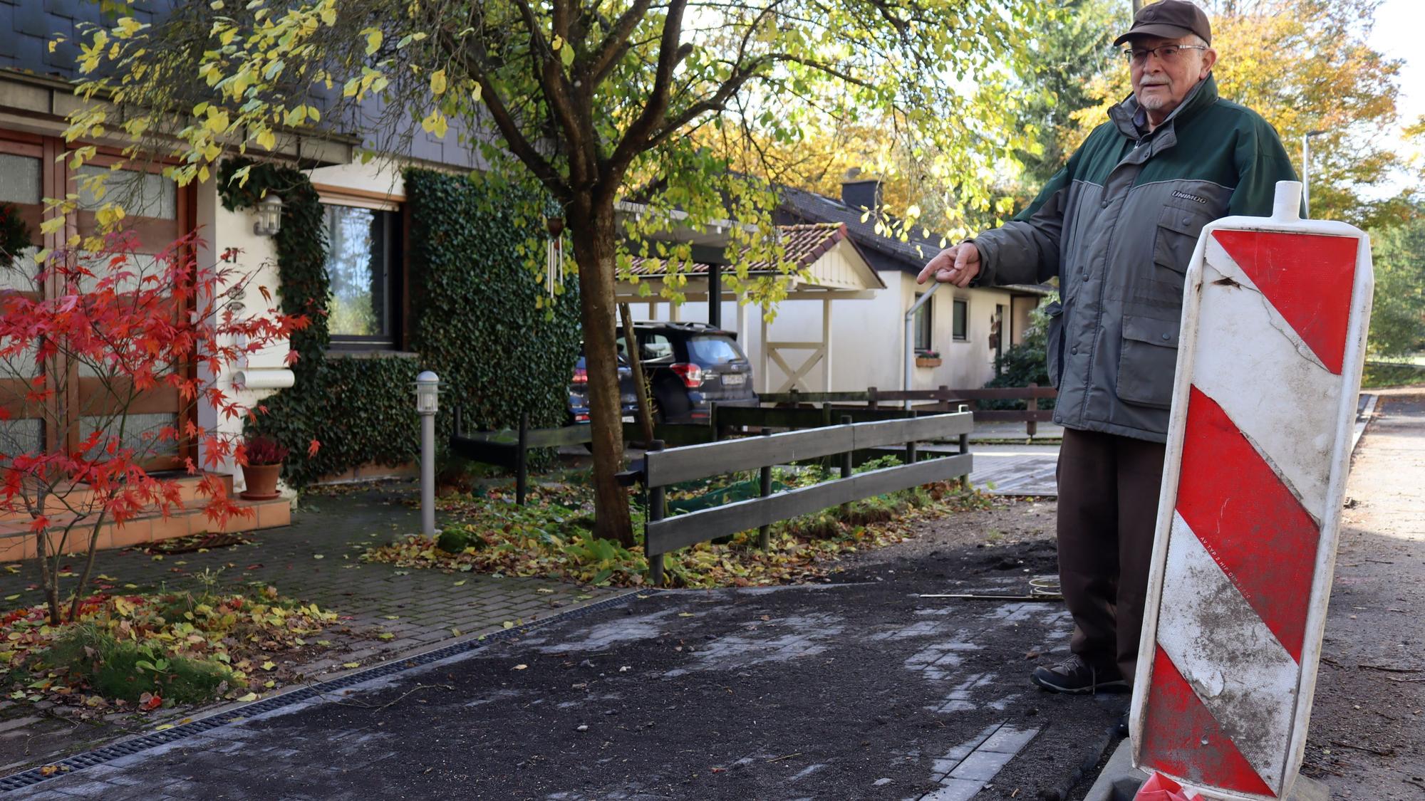 Michael Bolten zeigt auf die abschüssige Zuwegung zwischen Straße und seinem Grundstück.