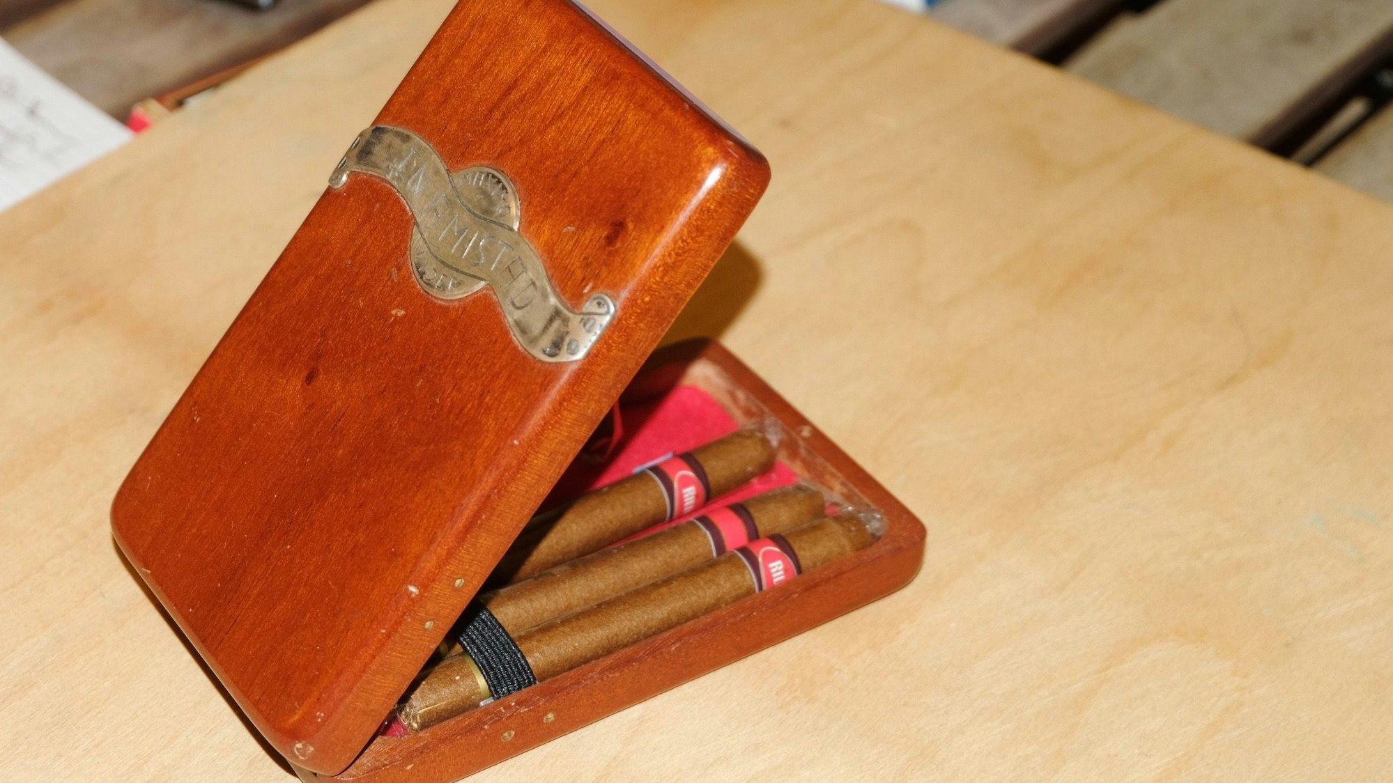 Eine Holzbox enthält Zigarillos. Verziert ist sie mit einem Metallornament.