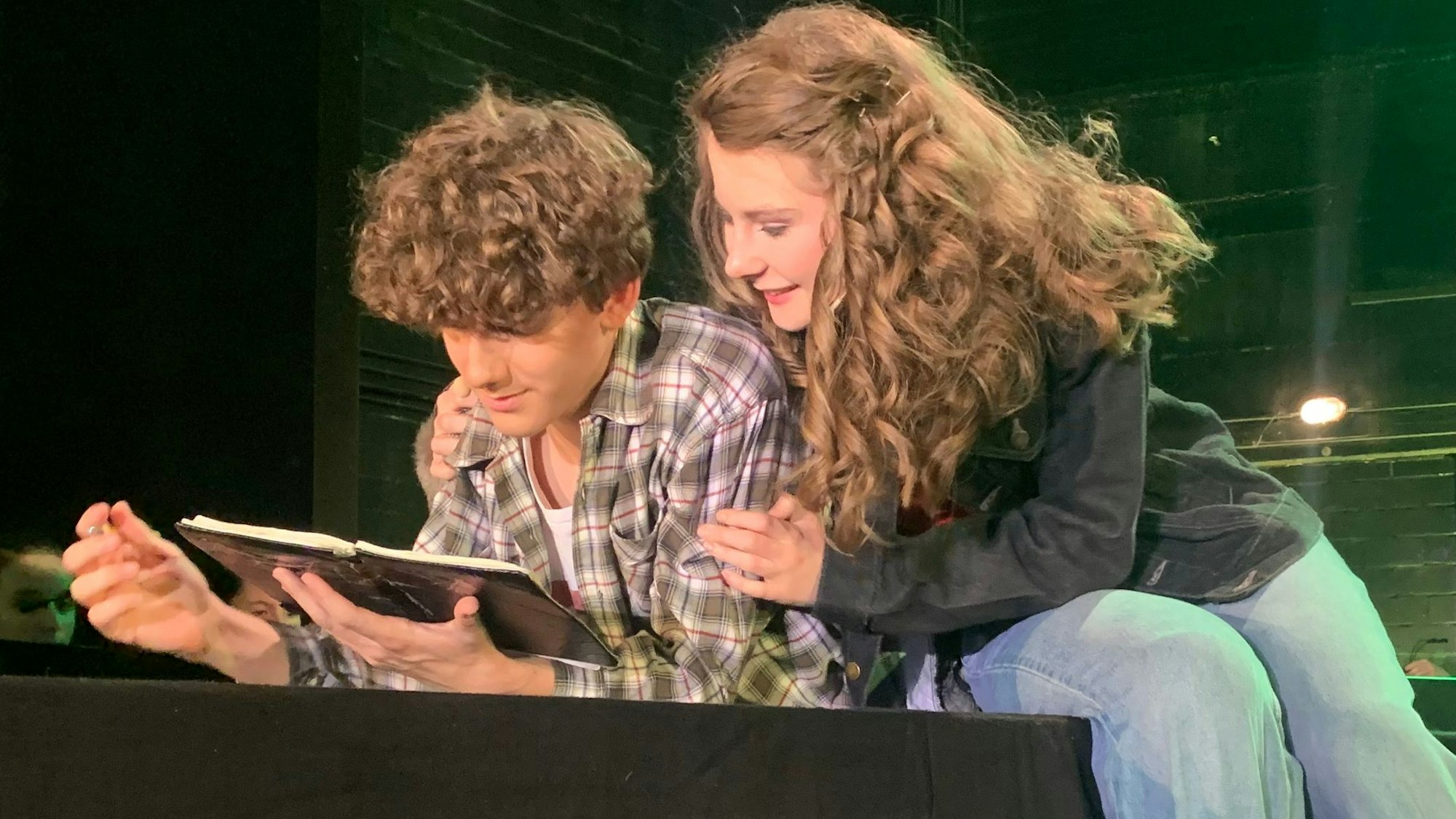 Die verliebten Hauptdarsteller Tom und Anne lesen zusammen in einem Buch beim Oberstufenmusical Chasing Shadow am Rhein-Sieg-Gymnasium.
