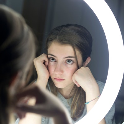 Junges Mädchen schaut sich im Spiegel an