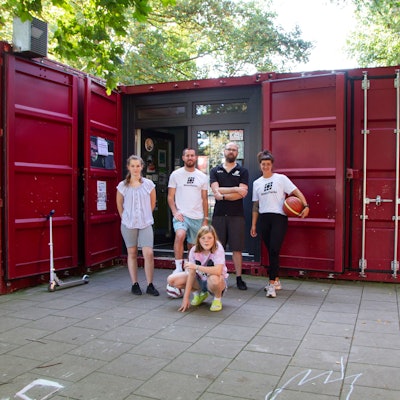 Das Team der„ Grembox“, der Jugendeinrichtung der „Rheinflanke“ in Gremberghoven, steht vor einem ehemaligen Seecontainer, der jetzt eine Jugendeinrichtung ist.