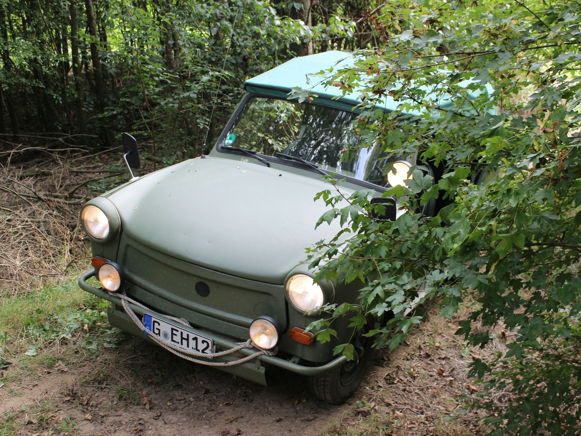 Der Trabi auf einem unebenen Waldweg.
