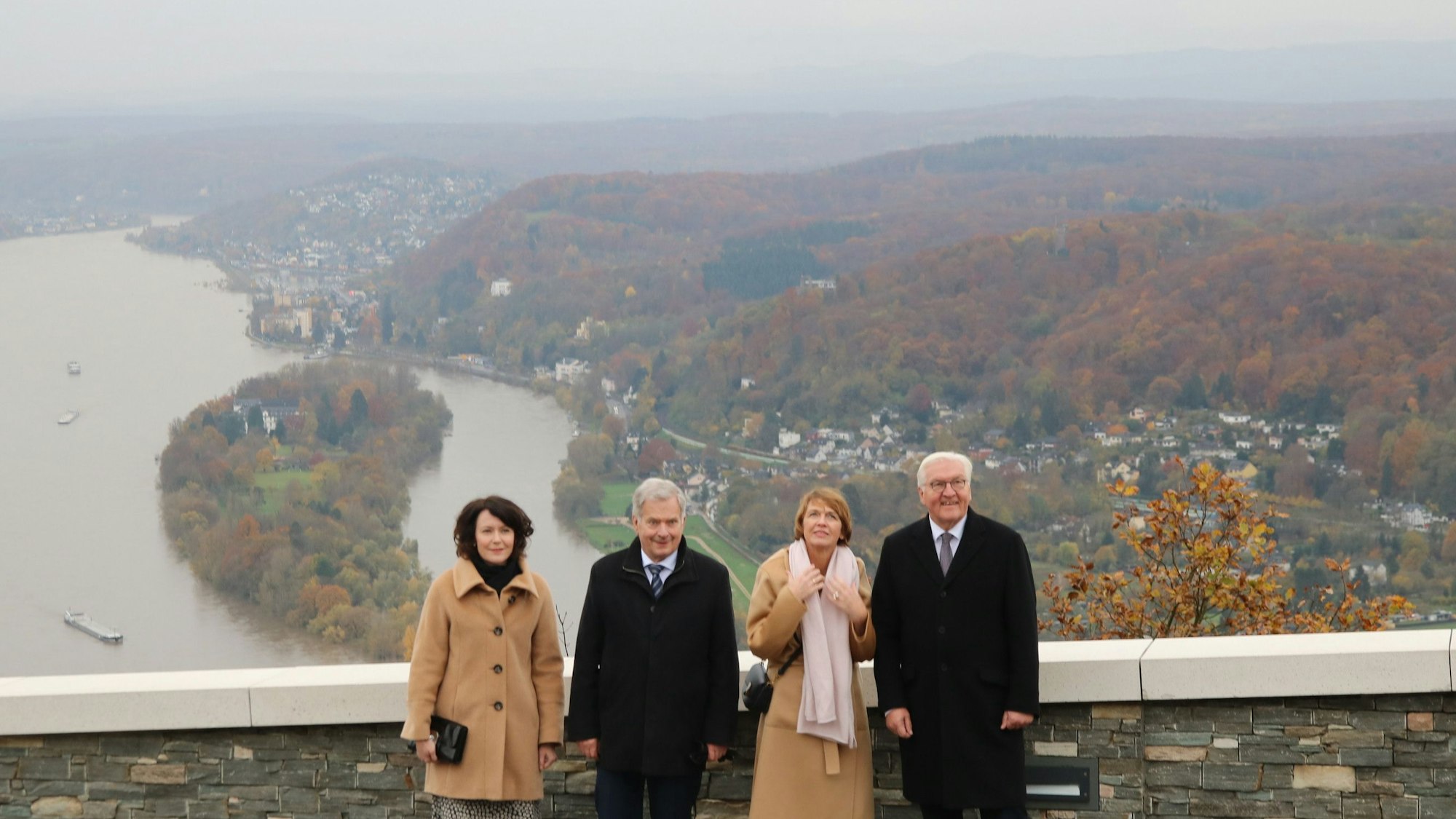 Zwei Frauen und zwei Männer stehen auf dem Drachenfelsplateau, im Hintergrund ist das Rheintal mit der Insel Nonnenwerth zu sehen.