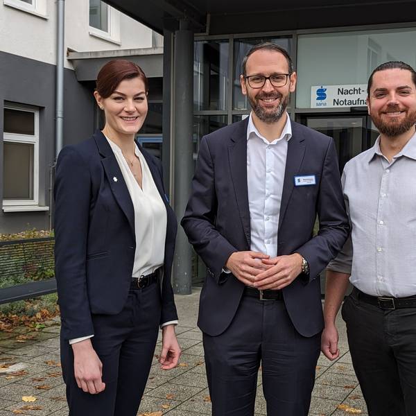 Eine Frau und zwei Männer vor der Nacht- und Notaufnahme des Sana-Krankenhauses in Hürth.