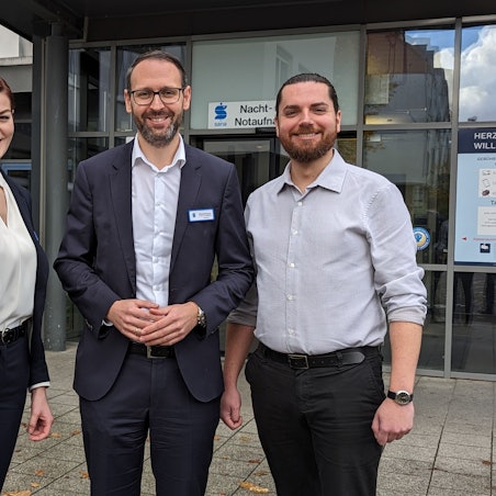 Eine Frau und zwei Männer vor der Nacht- und Notaufnahme des Sana-Krankenhauses in Hürth.
