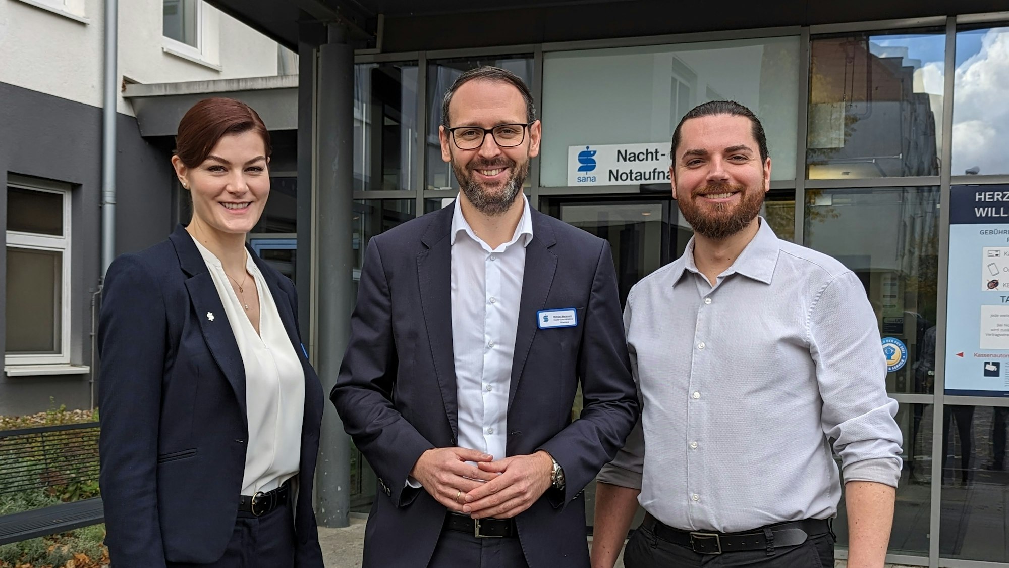 Eine Frau und zwei Männer vor der Nacht- und Notaufnahme des Sana-Krankenhauses in Hürth.