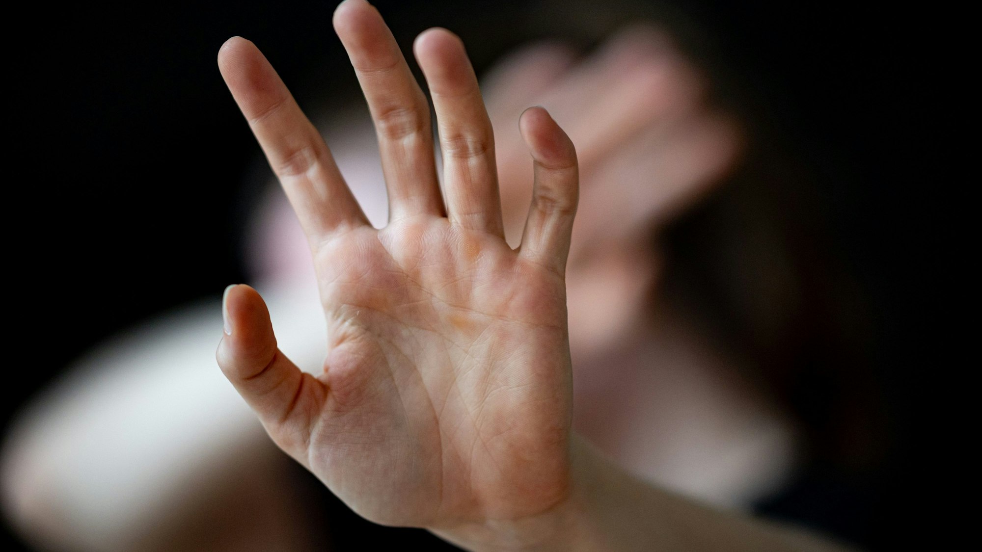 Eine Frau hält ihre Hände vor das Gesicht (Gestellte Szene).