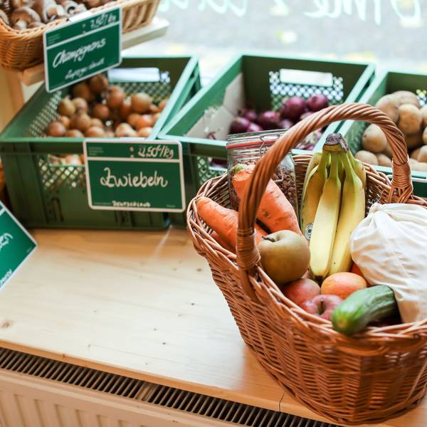 Ein zugeschnürtes Stoffsäckchen mit Nudeln liegt neben Obst und Gemüse in einem Korb in einem "Unverpackt"-Laden.