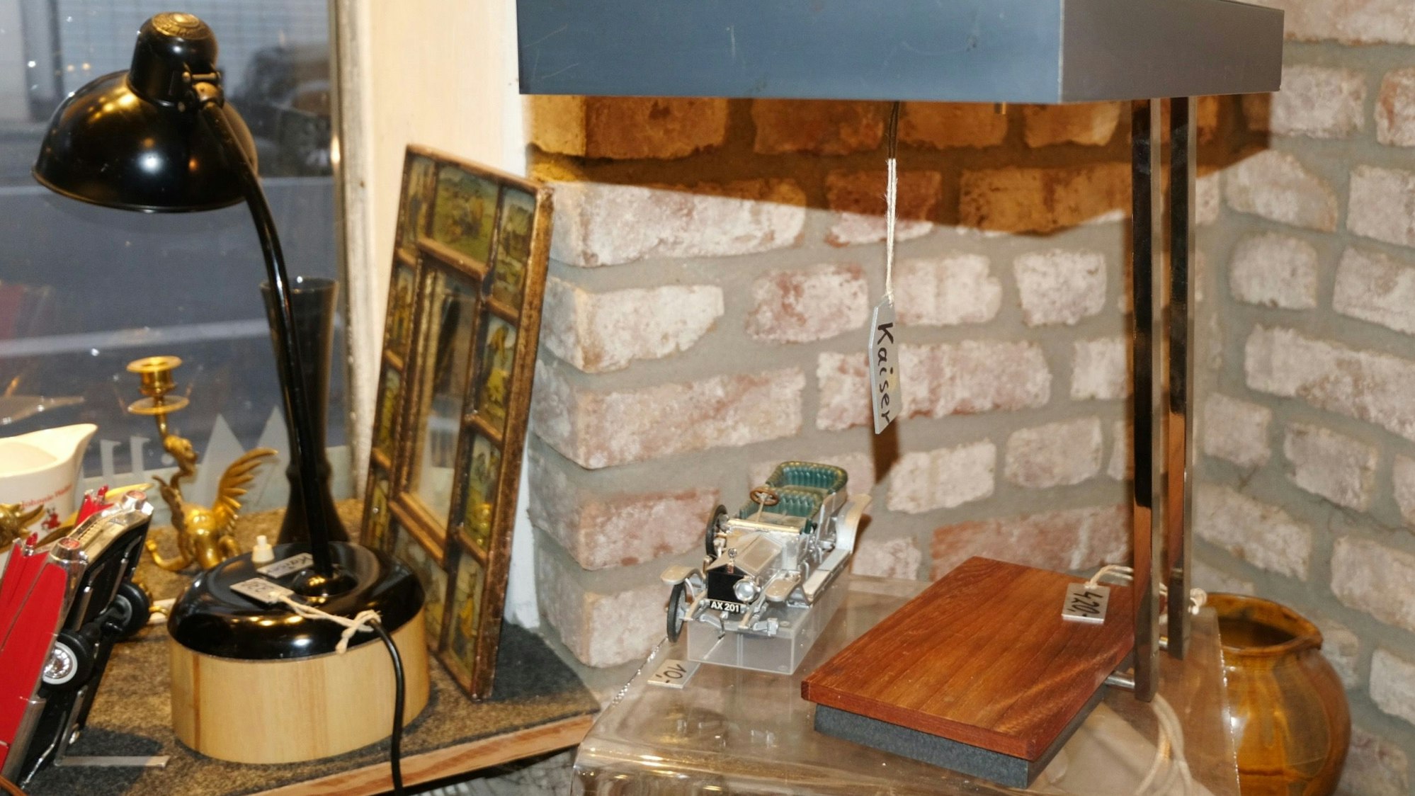 Eine Lampe mit rechteckigem Schirm und Holzfuß steht auf einem Tischchen.