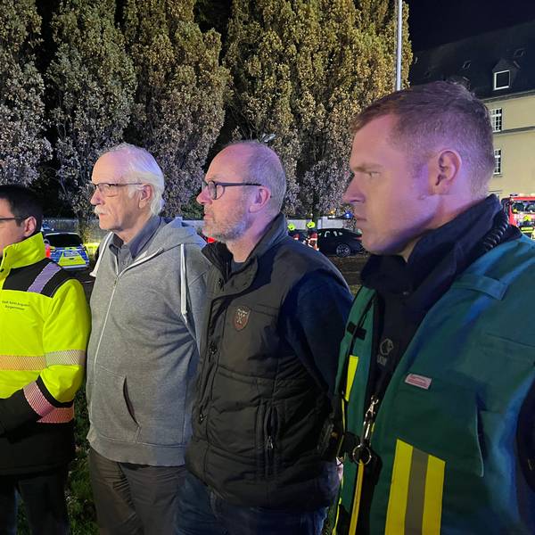 Mehrere Männer stehen aufgereiht vor einem Mikrofon.