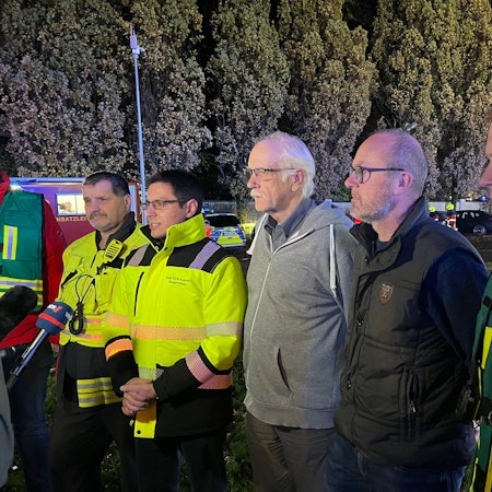 Mehrere Männer stehen aufgereiht vor einem Mikrofon.