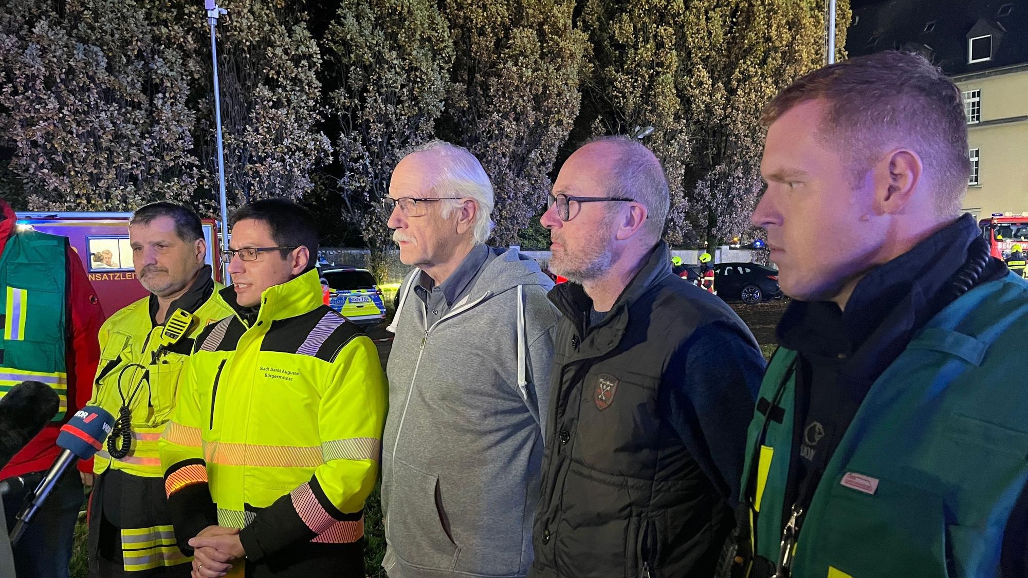 Mehrere Männer stehen aufgereiht vor einem Mikrofon.