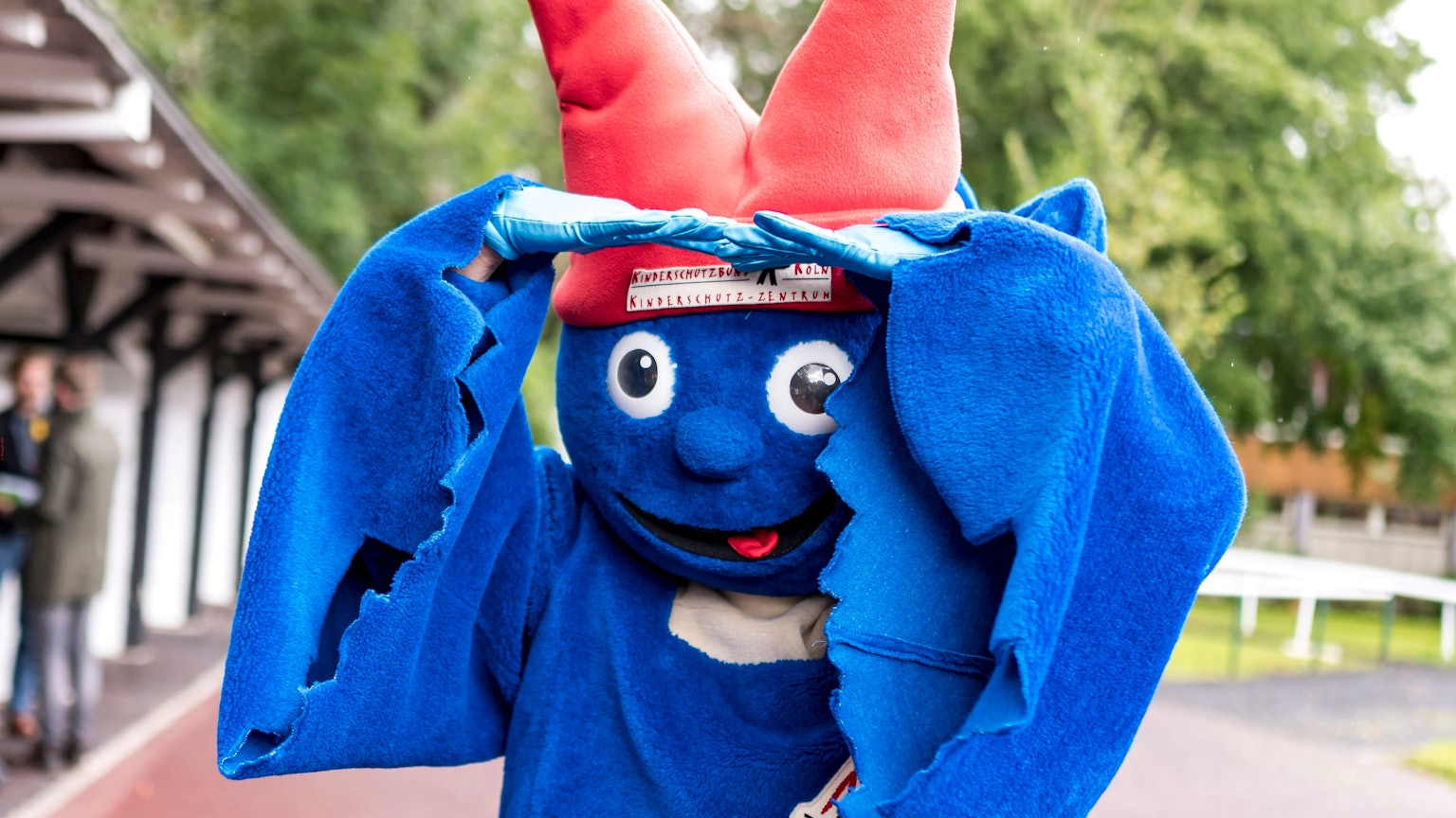 Das Maskottchen vom Kinderschutzbund Köln ist ein laues Männchen mit einem roten Hut, der aussieht wie die Spitzen des Kölner Doms.