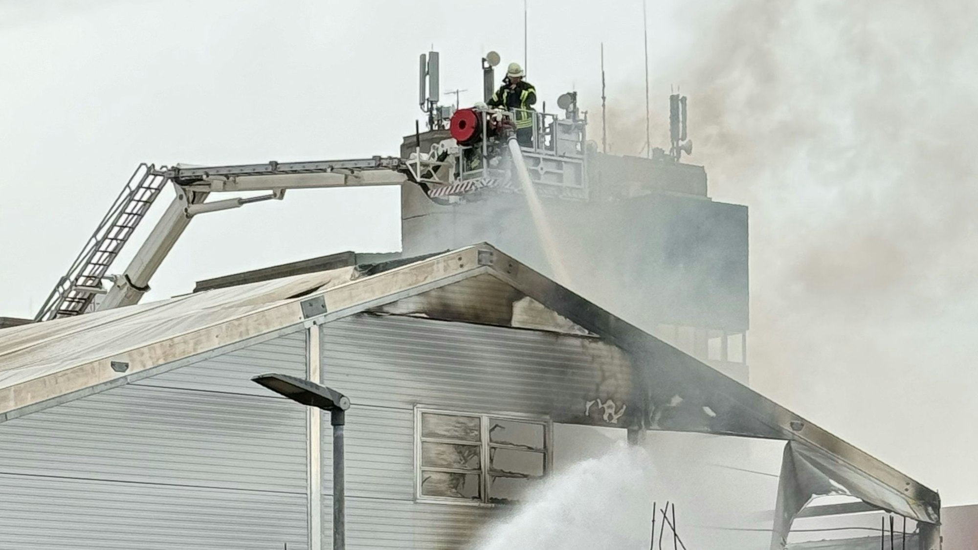 Das Bild zeigt mehrere Feuerwehrmänner im Korb einer Gelenkmastbühne.