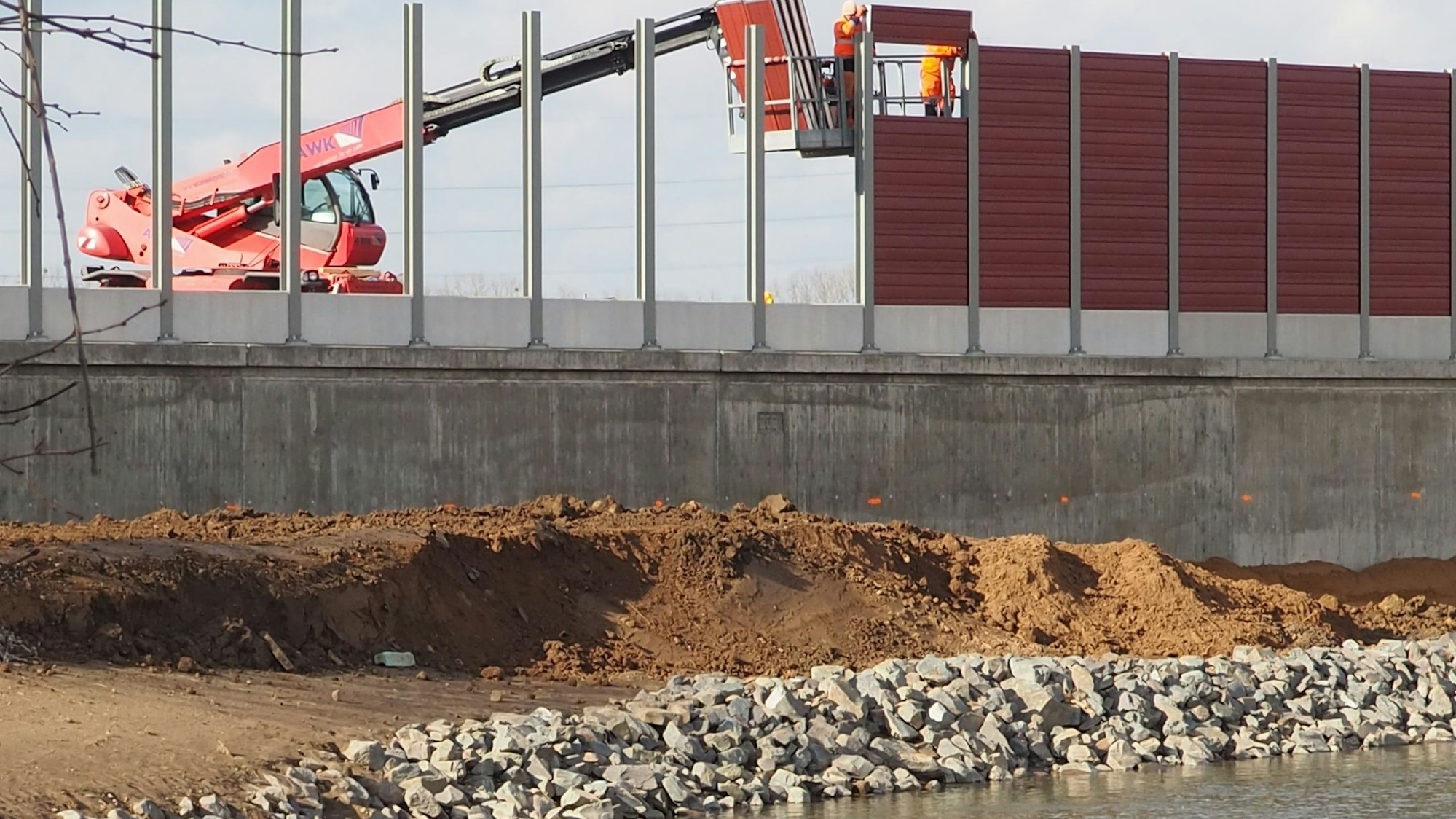 Auf dem Foto ist zu sehen, wie Paneele in die Lärmschutzwand eingesetzt, die nach der Flut neu errichtet werden musste.