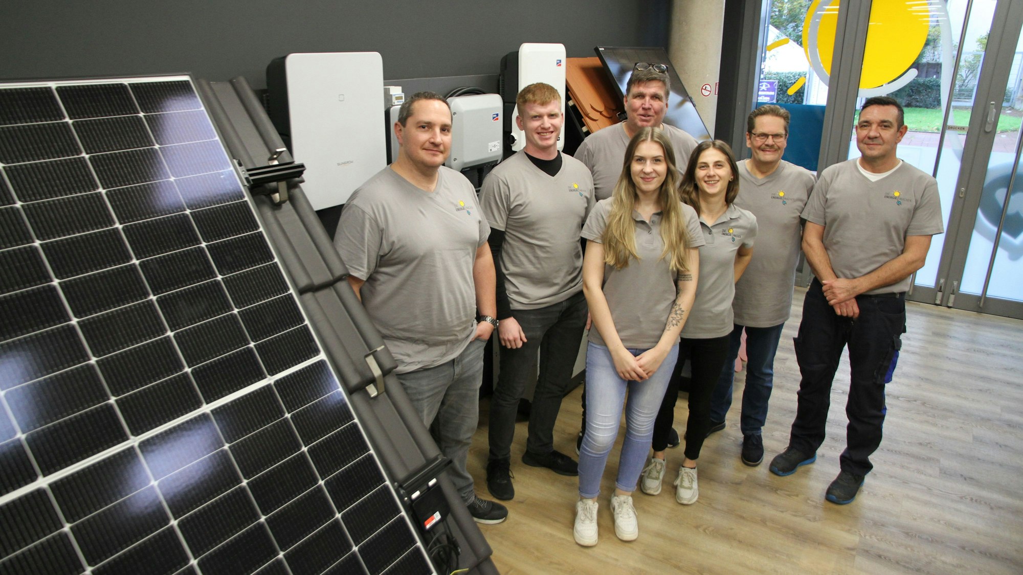 Fünf Männer und zwei Frauen stehen neben einem Photovoltaikmodul