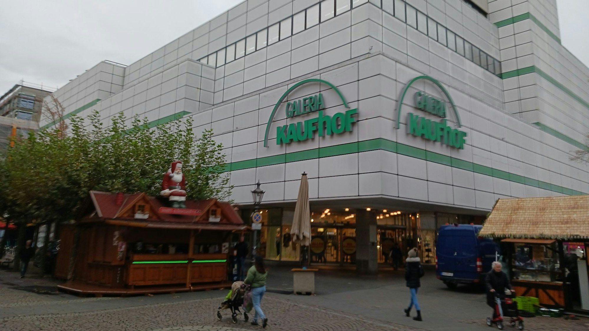 Ein Warenhaus in einer Fußgängerzone, im Vordergrund ein Glühweinstand