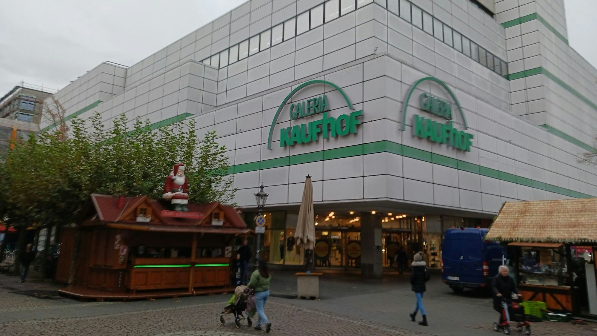 Ein Warenhaus in einer Fußgängerzone, im Vordergrund ein Glühweinstand