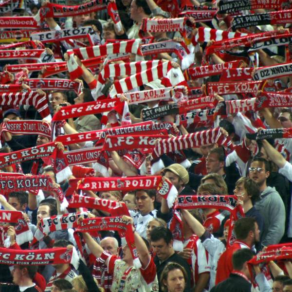 Anhänger des 1. FC Köln halten ihre Fan-Schals in die Höhe.