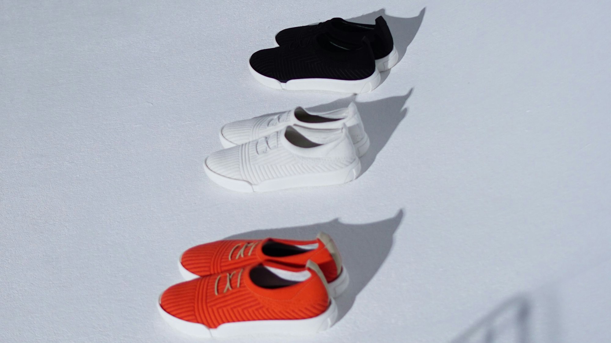 Drei Turnschuhe in den Farben schwarz, orange-rot und weiß