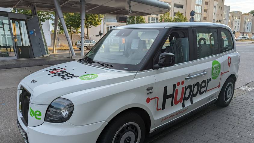 Ein Großraumtaxi mit der Aufschrift Hüpper am Busbahnhof in Hürth-Mitte.