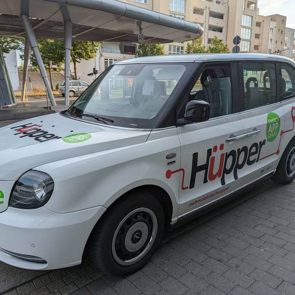 Ein Großraumtaxi mit der Aufschrift Hüpper am Busbahnhof in Hürth-Mitte.