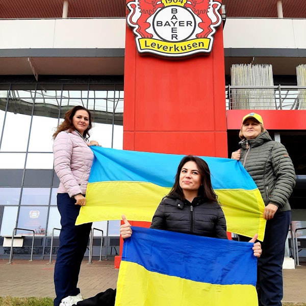 Die Ukrainerinnen (v.l.) Bilozin Liubov, Viktoriia Zhevlova und Nadiia Shepel stehen mit Ukraine-Flaggen vor der Bay-Arena, wo am kommenden Montag, 20. November,das Qualifikationsspiel zur Fußball-Europameisterschaft 2024 zwischen der Ukraine und Italien stattfindet.