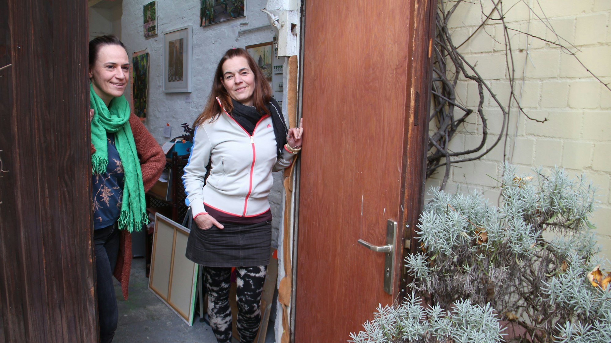 Zwei Frauen schauen bei geöffneter Tür aus ihrem Atelier nach draußen.