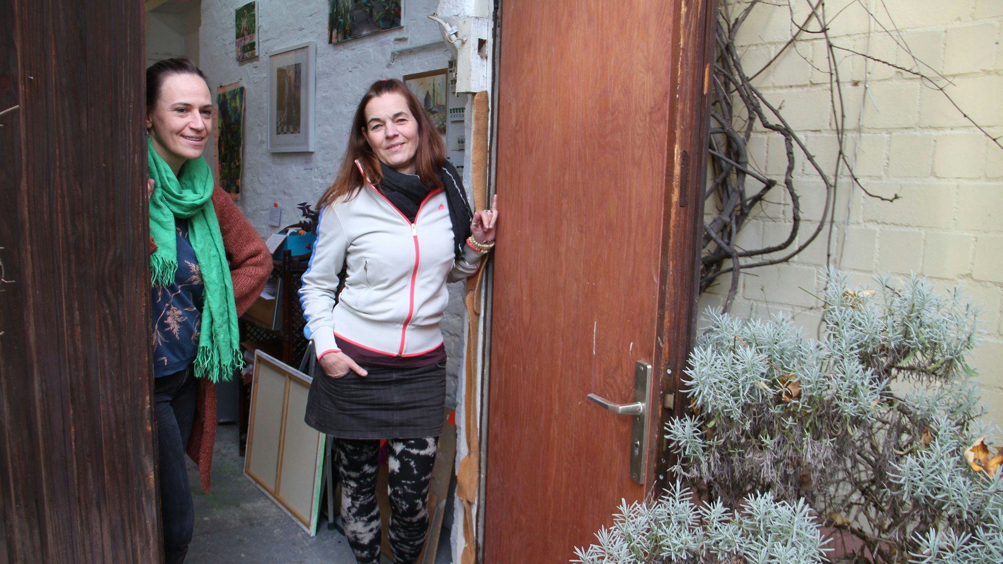 Zwei Frauen schauen bei geöffneter Tür aus ihrem Atelier nach draußen.
