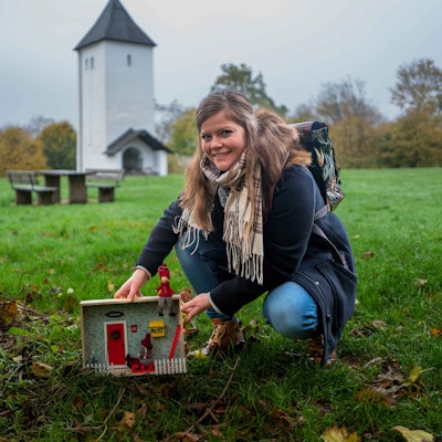 Das Bild zeigt Patricia Dreesbach vor dem Swister Turm, wie sie an einem Baum eine Wichtelwohnung aufstellt.
