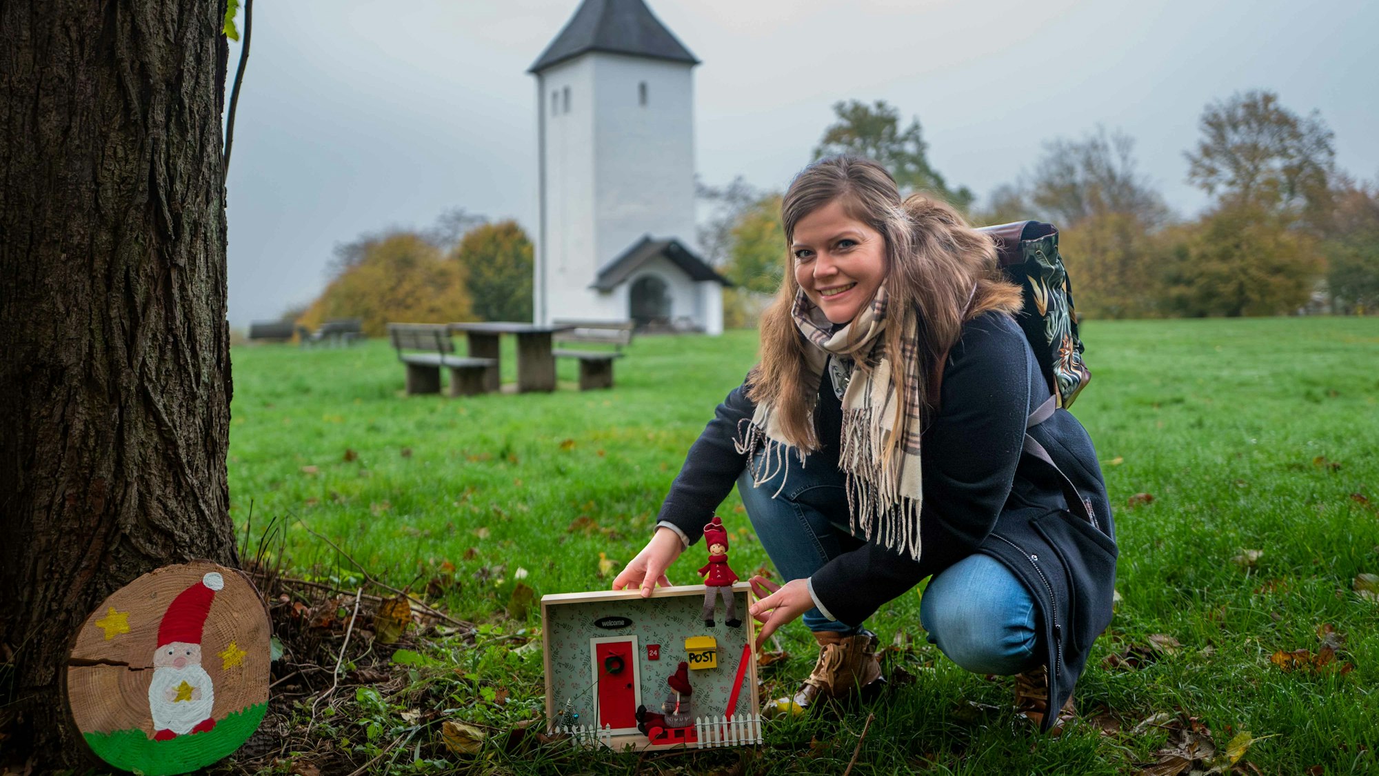 Das Bild zeigt Patricia Dreesbach vor dem Swister Turm, wie sie an einem Baum eine Wichtelwohnung aufstellt.