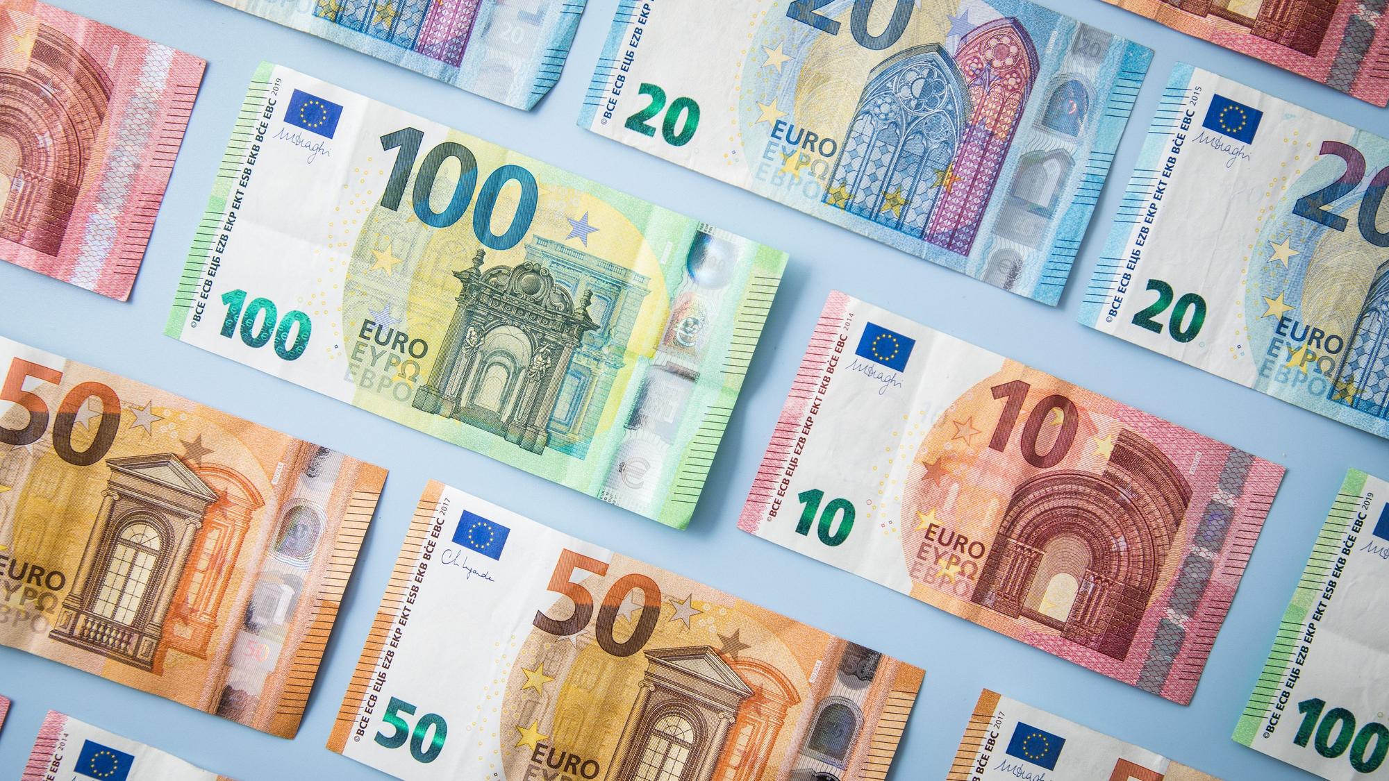 Geldscheine sind vor einem blauen Hintergrund nebeneinander aufgereiht.(Symbolbild)