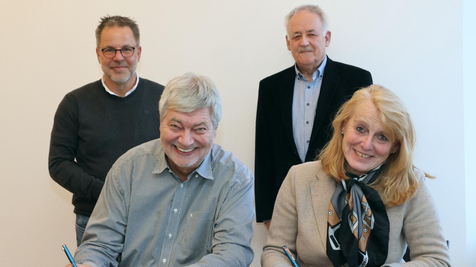 Hilko Redenius und Monika Lichtinghagen-Wirths sitzen an einem Tisch vor Dokumenten, die sie mit ihrer Unterschrift versehen.