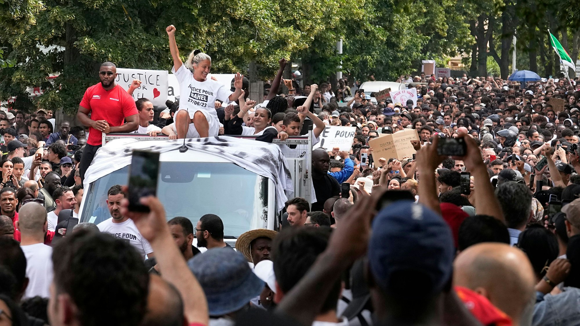 29.06.2023, Frankreich, Nanterre: Die Mutter eines getöteten 17-jährigen sitzt auf einem Lastwagen und ballt ihre gestreckte Faust während eines Trauermarsches.