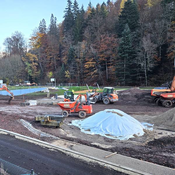 Blick auf die Baustelle mit mehreren Baggern und Arbeitern.