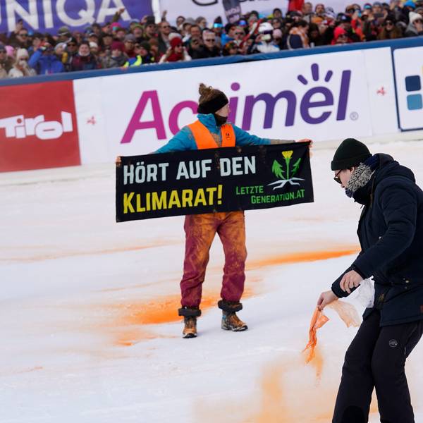Ein Demonstrant der Letzten Generation versprüht Farbe im Zielbereich eines alpinen Skiweltcup-Slaloms der Herren in Gurgl.