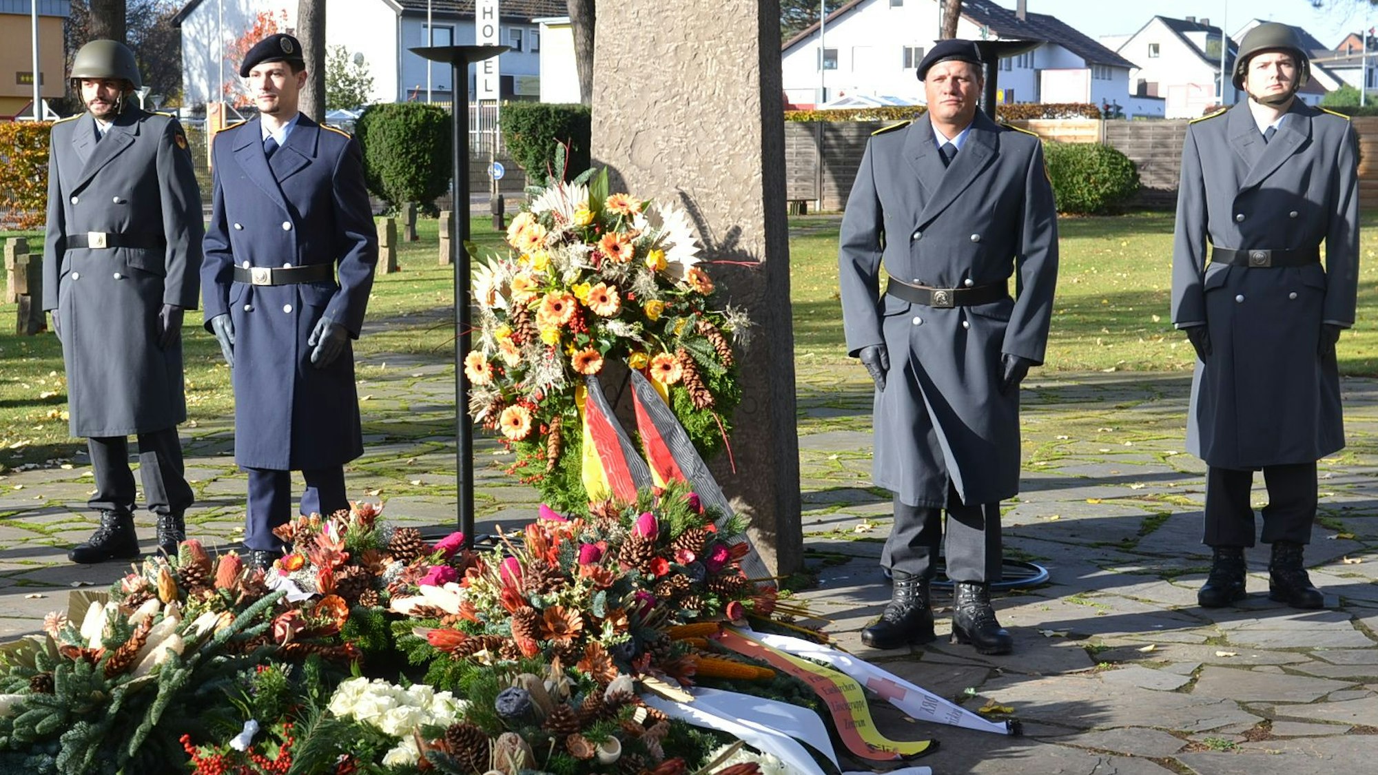 Vier Soldaten einer Ehrenwache steht auf dem Euskirchener Friedhof am Ehrenmal, vor dem zahlreiche Kränze abgelegt sind.