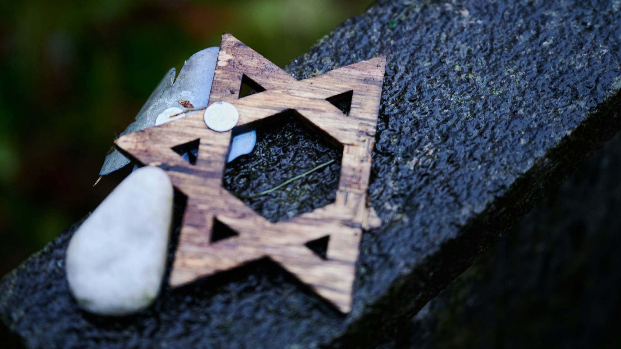 Ein abgebrochener Davidstern liegt während der Gedenkveranstaltung am 19. November 2023 zum Volkstrauertag auf dem Jüdischen Friedhof Berlin-Weißensee auf einem Grabstein.