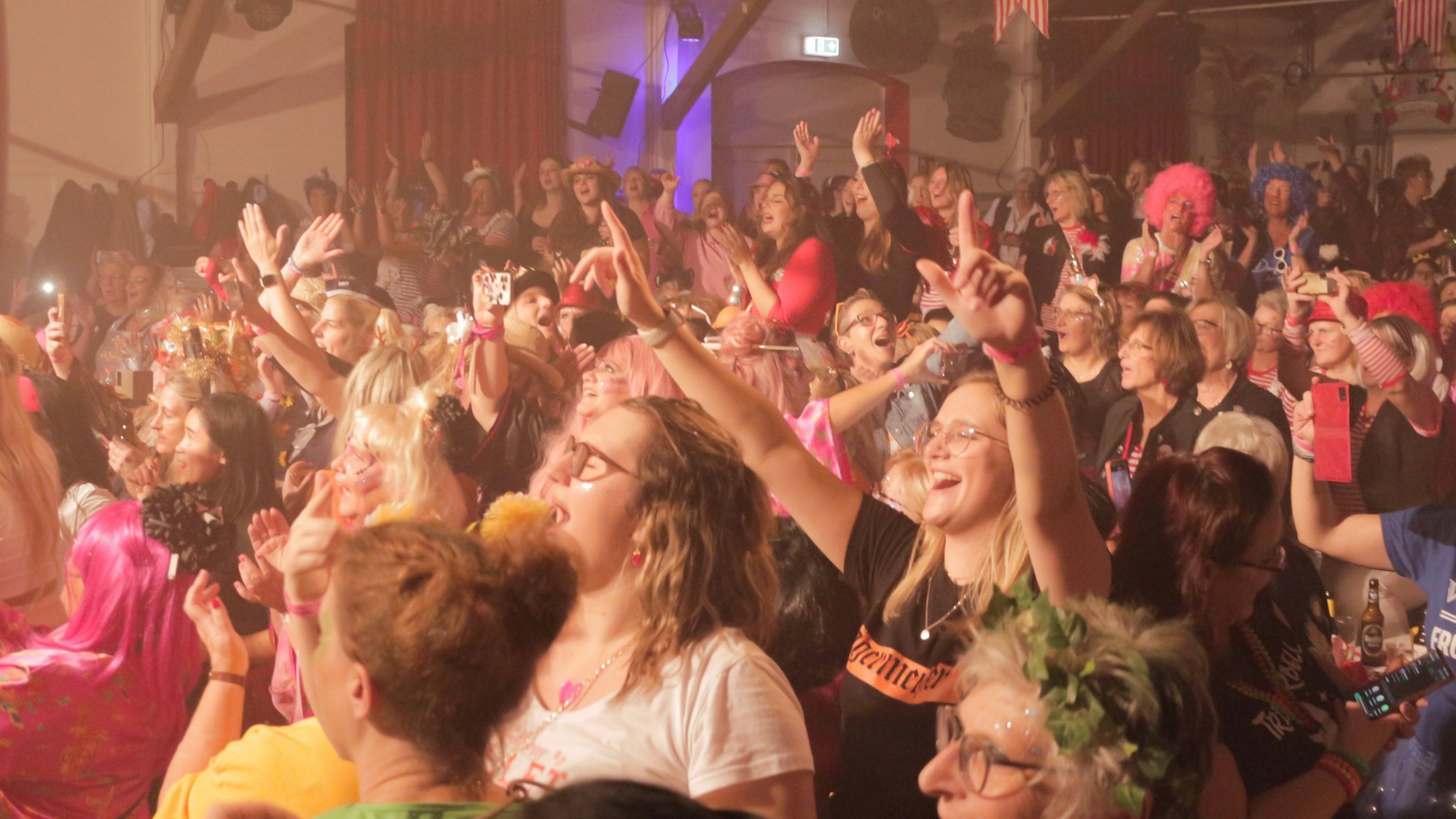 Bunt kostümierte Frauen feiern im voll besetzten Iversheimer Dorfsaal ausgelassen Karneval.
