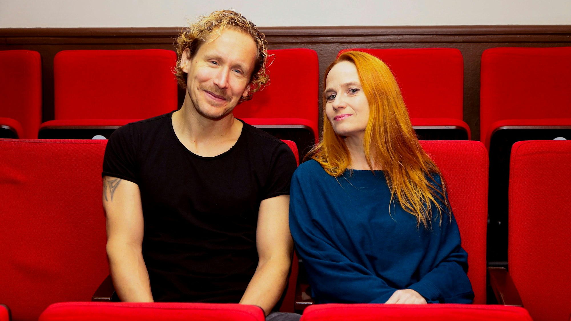 Flo Peil und Vera Bolten sitzen auf den roten Sitzen im Theater