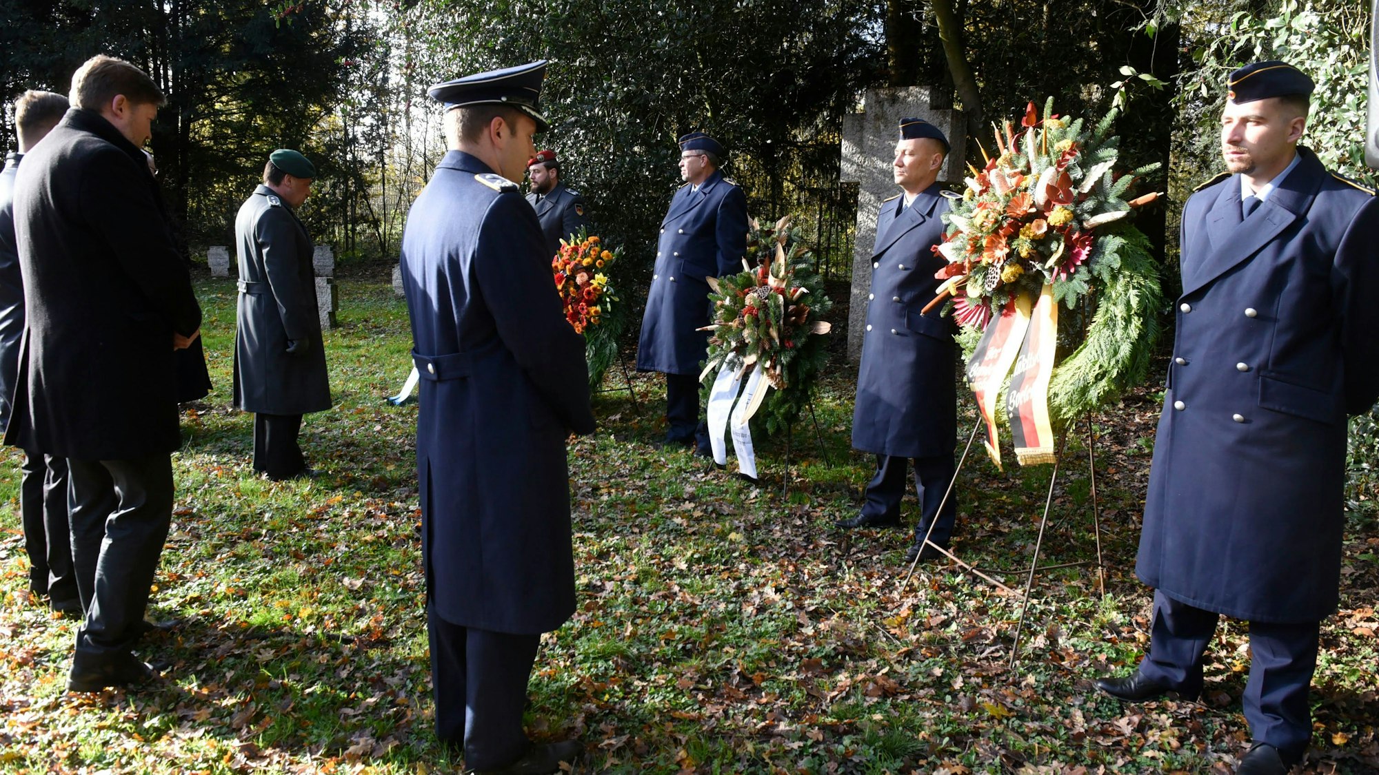 Auf dem Bild sind Männer zu sehen, die Kränze an einem Mahnmal abgelegt haben.