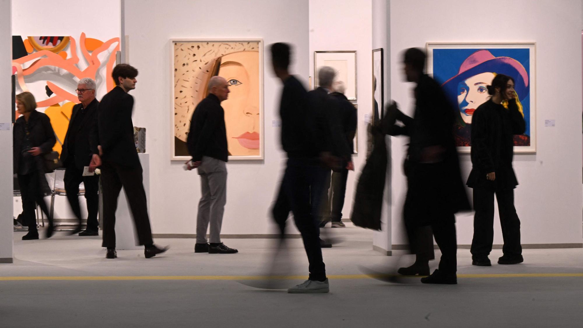 Die Silhouetten von Messebesuchern sind vor einem Messestand zu sehen.