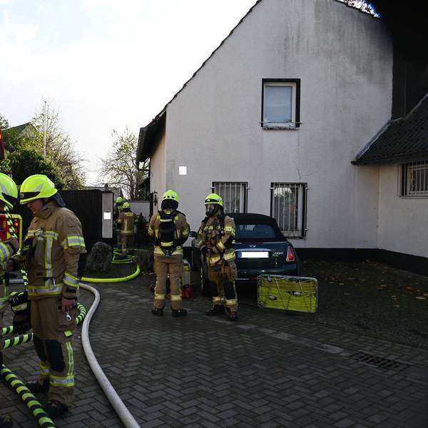 Auf dem Foto sind mehrere Feuerwehrleute vor dem Brandhaus zu sehen. Das Feuer ist bereits gelöscht.