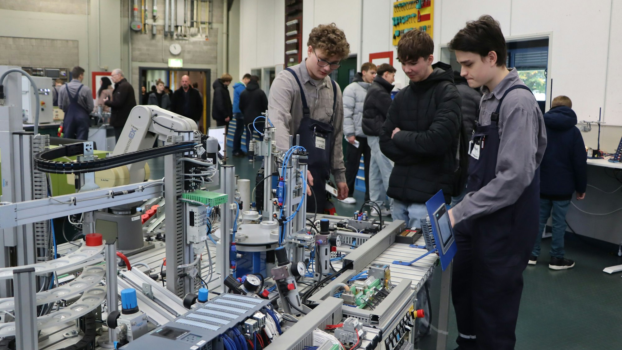 Drei junge Männer stehen an einer Maschine.