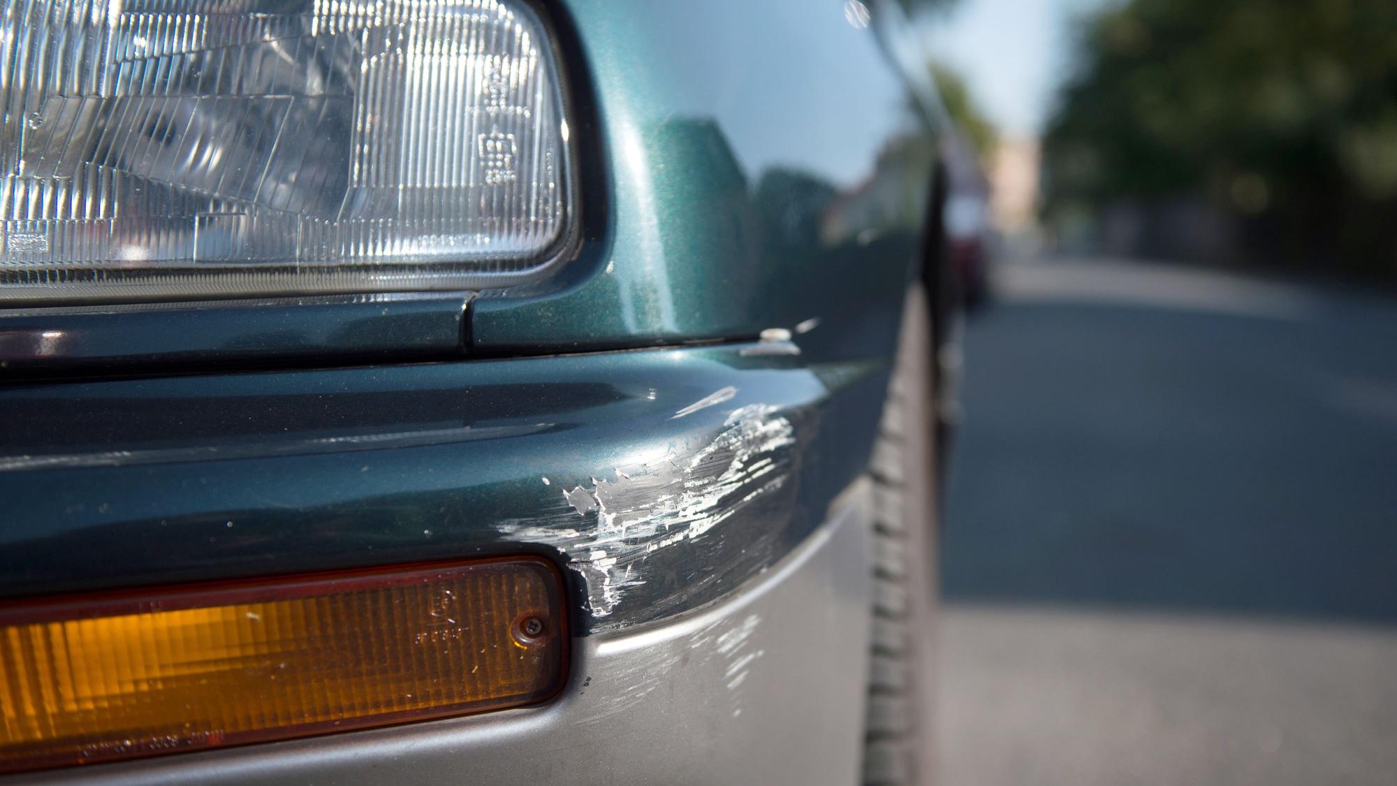 Am Stoßfänger eines geparkten Personenkraftwagens sind Spuren eines Unfalls zu sehen.