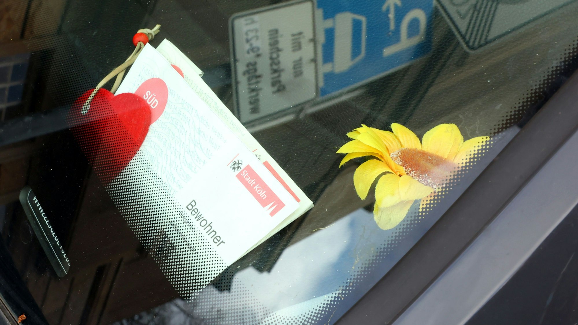 Ein Anwohnerparkausweis liegt hinter einer Windschutzscheibe.