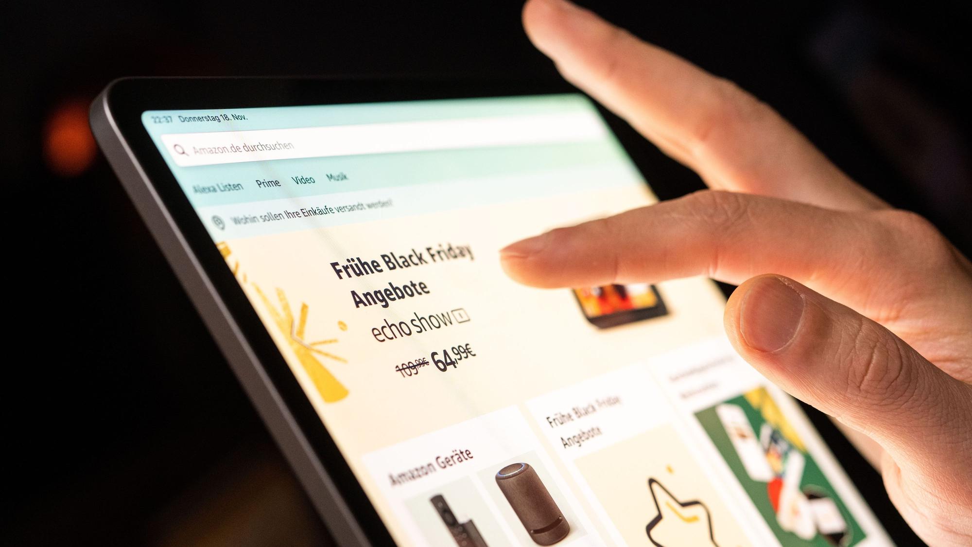 Eine Person tippt mit dem Finger auf ein Tablet, auf dem ein Online-Shop mit Werbung für den Black Friday geöffnet ist.